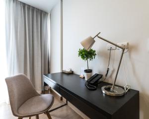 a desk with a lamp and a chair in a room at Canalis Suvarnabhumi Airport Hotel in Lat Krabang