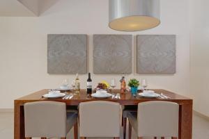 a dining room table with white chairs and a light fixture at Herdade dos Salgados, Beach Villa, 3 Suites in Guia