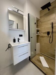 een badkamer met een witte wastafel en een douche bij URBAN APARTMENTS PREMIUM Baildona 18A with GARAGE in Katowice