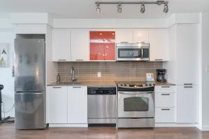 a kitchen with white cabinets and stainless steel appliances at Chinatown Chic Suite by Iris Properties! in Victoria