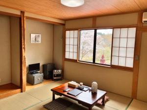 uma sala de estar com uma mesa e uma janela em 幡谷温泉 ささの湯 em Hataya