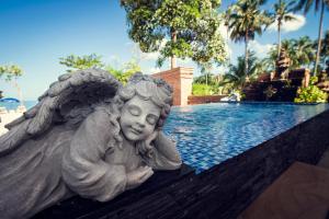 uma estátua de um anjo sentado ao lado de uma piscina em The White Knot Koh Chang em Ko Chang