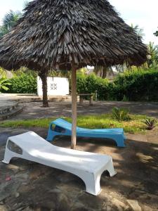 a straw umbrella and two beds under it at Alooma Studio homes in Galu