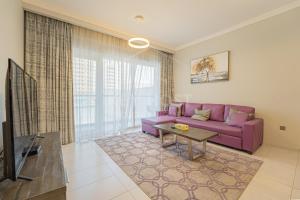 a living room with a purple couch and a tv at KeyHost - 1BR Apartment Near Five Hotel JVC - K141 in Dubai