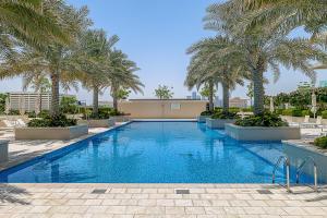 a swimming pool with palm trees in a resort at Frank Porter - Al Saadiyat Island in Abu Dhabi