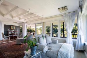 a living room with a couch and windows at Prana Lodge in Chintsa