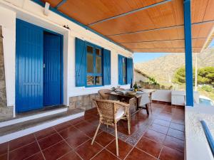 een patio met blauwe deuren en een tafel en stoelen bij Villa Portús in Portús