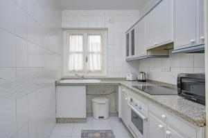 cocina blanca con lavabo y aseo en New Arab Baths Apartament, en Granada