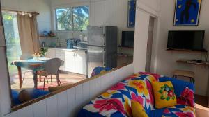 a living room with a couch and a kitchen with a table at Barefoot Base Tupapa in Rarotonga