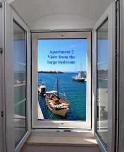 una ventana con una foto de un barco en el agua en Apartments Best Location, en Supetar