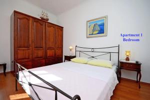 1 dormitorio con 1 cama y armario de madera en Apartments Best Location, en Supetar