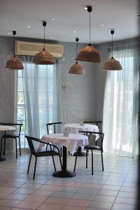 un comedor con mesas, sillas y luces colgantes en Anamar Skiathos Hotel, en Punta