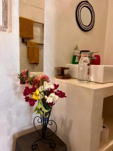 a vase of flowers on a table in a bathroom at peeKAboo Diani Beach in Diani Beach