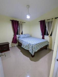 een slaapkamer met 2 bedden en paarse gordijnen bij Oviedo Pedernales, Casa Lolón 