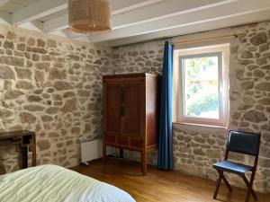 ein Schlafzimmer mit Steinmauern, einem Fenster und einem Stuhl in der Unterkunft Maison de charme in Thil-sur-Arroux