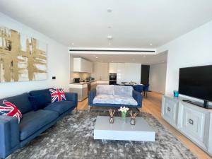 a living room with a blue couch and a tv at Battersea Power Apartments in London