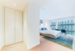 a white bedroom with a bed and a dining room at Battersea Power Apartments in London