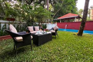 a backyard with chairs and a couch and a table at StayVista at Villa Arcadia with Alfresco Dining in Candolim