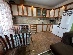 uma cozinha com armários de madeira, uma mesa e um frigorífico em Къща Олеандър em Ivajlovgrad