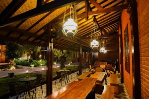 un ristorante con tavoli e sedie in legno e lampadari a braccio di Ndalem Mataram a Banyuwangi