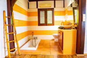 La salle de bains est pourvue d'une baignoire et d'un lavabo. dans l'établissement Villa au soleil couchant avec vue mer piscine sel, à Bouillante