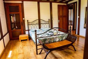 - une chambre avec un lit et un banc sur du parquet dans l'établissement Villa au soleil couchant avec vue mer piscine sel, à Bouillante