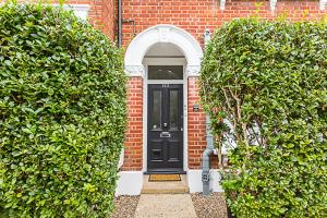 a black door in a brick house with two bushes at Gorgeous Clapham Flat in London