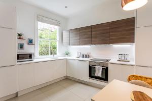 a white kitchen with wooden cabinets and a table at Gorgeous Clapham Flat in London