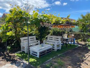 a garden with two white benches and a table at Casa Ameixeira in Carnota +9 photos