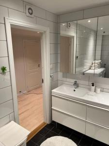 ein weißes Badezimmer mit einem Waschbecken und einem Spiegel in der Unterkunft Sentral 4-roms leilighet i Trollbakken in Tromsø