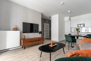 a living room with a couch and a tv at Symphony Modern Tower Aparthotel in Gdynia