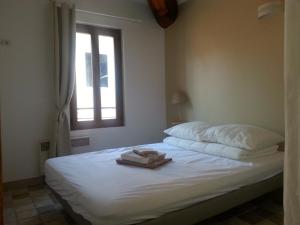 a bedroom with a bed with white sheets and a window at Location saisonnière dans le cœur historique – T3 pour 4 à 6 personnes in La Ciotat