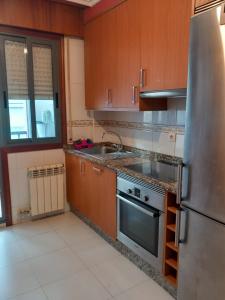 uma cozinha com armários de madeira e um frigorífico de aço inoxidável em RIOBO´S HOUSE em Vigo