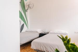 a bedroom with two beds and a floor lamp at Ocean Nomads Coworking in Arona