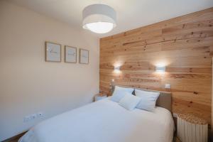 1 dormitorio con cama blanca y pared de madera en Chaleureux appartement 8 couchages #4 en Embrun