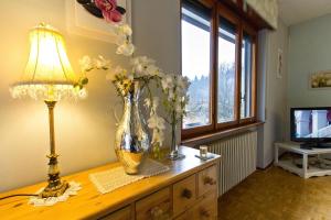 un jarrón de flores sobre una mesa de madera con una lámpara en Connie's Apartment - Happy Rentals, en  Monvalle 