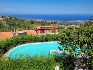 a swimming pool in front of a house at Etna Sunshine Rent Rooms in Puntalazzo