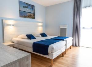 Habitación de hotel con 2 camas con sábanas azules en Arc en Ciel Oléron en Saint-Trojan-les-Bains