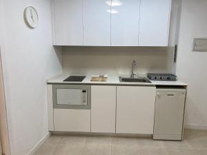 una pequeña cocina con armarios blancos y fregadero en Apartaments Puigcardener BX, en Manresa