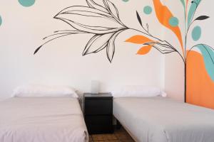 two beds in a room with a mural on the wall at Ocean Nomads Coworking in Arona