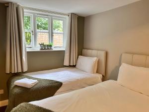 two beds in a room with two windows at The Unicorn Inn in Newton Solney