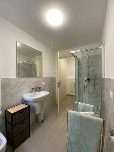 a white bathroom with a sink and a shower at Brothers' Suites in Pisogne