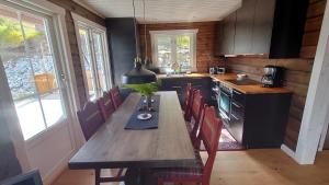 una cocina con una mesa de madera larga y sillas en Ny tømmerhytte en Tveiten