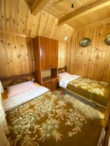 2 łóżka w pokoju z drewnianymi ścianami w obiekcie Vikendica Verusa w mieście Veruša