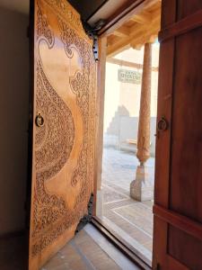 una puerta de madera abierta con vistas a un patio en Khiva Siyovush Hotel en Khiva