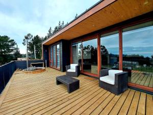 una terraza de madera con 2 sillas y un banco. en Lodge Pullay / 6 Personas, en Cobquecura