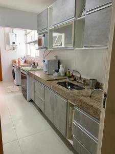 uma cozinha com armários de aço inoxidável e um lavatório em Refúgio praiano: Apto reformado a 100m da praia no Rio de Janeiro