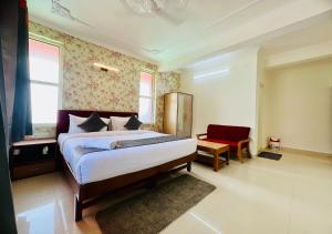 a bedroom with a large bed and a red chair at Hotel Starwud Kotagge Dharamshala in Dharmsala