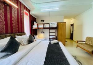 a bedroom with two beds and a couch and a bunk bed at Hotel Starwud Kotagge Dharamshala in Dharmsala