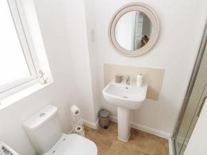 a white bathroom with a toilet and a mirror at Tŷ Glas in Bridgend +26 photos